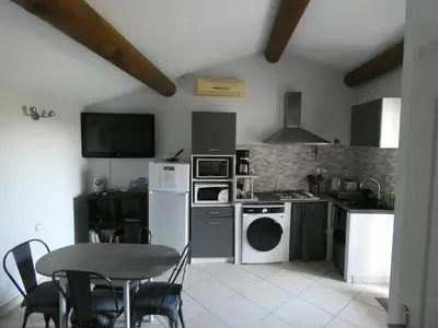 a kitchen with white appliances and a table and chairs at La Sarriette Provençale in Caumont-sur-Durance