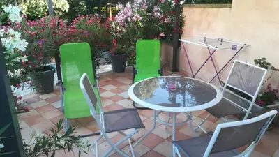 a patio with a table and chairs and flowers at Villa les Lauriers in Lioux
