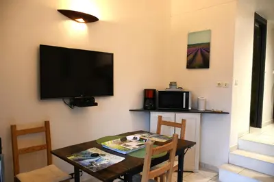a dining room with a table and a flat screen tv at Villa les Lauriers in Lioux