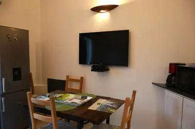 a dining room table with a television on the wall at Villa les Lauriers in Lioux