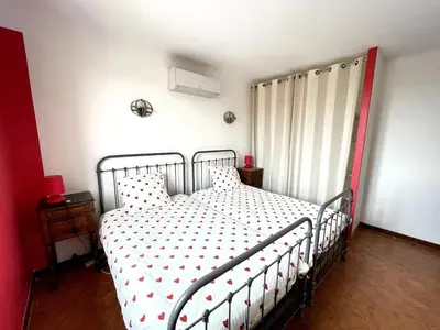 a bedroom with a metal bed with white sheets and red accents at Le Jardin d'Auguste in Roussillon