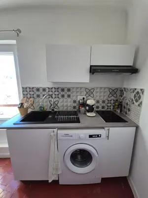a kitchen with a sink and a washing machine at Cosy downtown studio in Apt