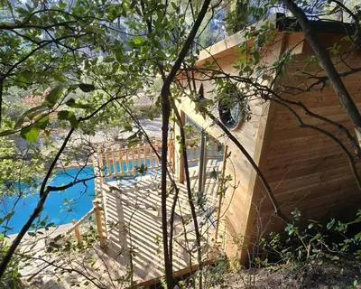 a house with a wooden staircase next to a pool at La Cabane Aixoise Piscine & Jacuzzi in Aix-en-Provence