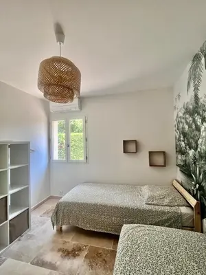 a bedroom with two beds and a chandelier at Maison du Ventoux in Mormoiron