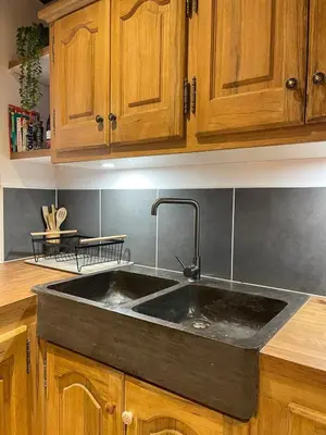 a kitchen with a black sink and wooden cabinets at Maison de charme in Apt