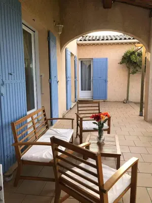 a patio with two benches and a table with flowers at Jolie studio en Provence! in Pierrevert