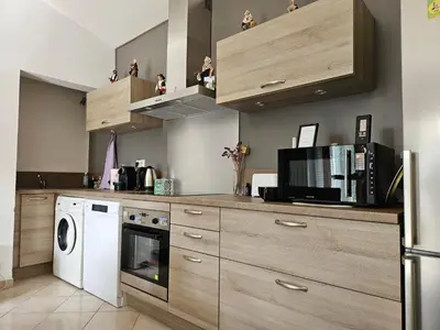 a kitchen with wooden cabinets and a washer and dryer at Chez Cathy in Pernes-les-Fontaines