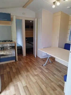 a living room with a table and a kitchen at Comme Chez Vous Au Camping Des Iscles in La Roque-dʼAnthéron