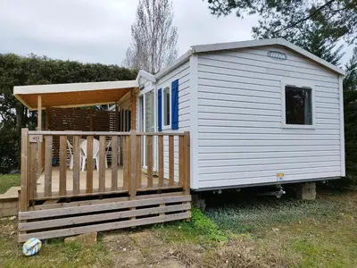 a tiny house with a porch and a deck at Comme Chez Vous Au Camping Des Iscles in La Roque-dʼAnthéron