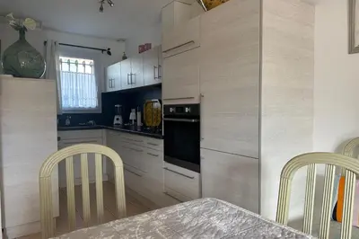 a kitchen with white cabinets and a table and chairs at At Tinou's spacious quiet house with garden for 2 people in LʼIsle-sur-la-Sorgue