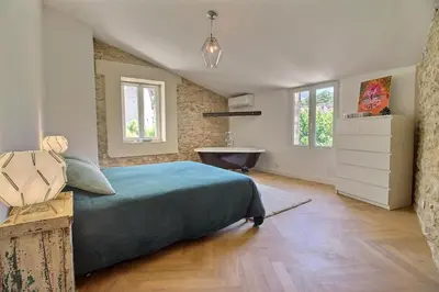 a bedroom with a bed and a bathroom with a sink at Le Mas Rose Thé in Robion en Luberon