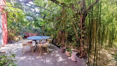 a patio with a table and chairs and trees at La Verrière des Songes in Robion en Luberon