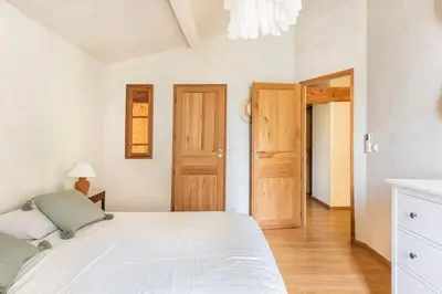 a bedroom with a white bed and wooden doors at Mas de 190m2 Climatisé avec Piscine et Cuisine d'été - 10 pers in La Fare-les-Oliviers