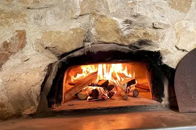 a brick oven with a fire in it at Mas de 190m2 Climatisé avec Piscine et Cuisine d'été - 10 pers in La Fare-les-Oliviers