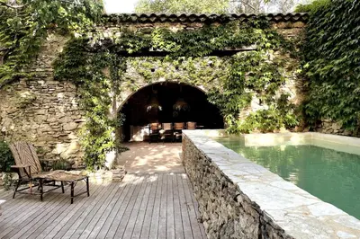 a bench sitting on a patio next to a swimming pool at Mas de 190m2 Climatisé avec Piscine et Cuisine d'été - 10 pers in La Fare-les-Oliviers