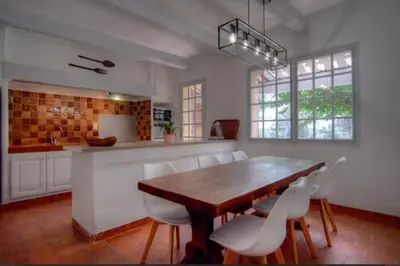 a kitchen with a wooden table and white chairs at Villa Martine, authentic family home in Rognes