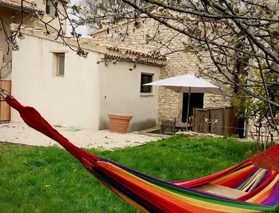 a hammock in a yard with a house and an umbrella at 15 rue des pierres seches in Ferrassières
