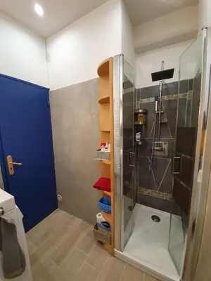 a bathroom with a shower with a blue door at Appartement atypique dans un ancien couvent in LʼIsle-sur-la-Sorgue