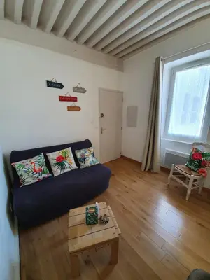 a living room with a couch and a table at Appartement atypique dans un ancien couvent in LʼIsle-sur-la-Sorgue