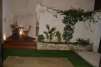 a patio with a table and some plants on the wall at Maison en coeur de ville in LʼIsle-sur-la-Sorgue