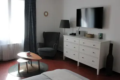 a living room with a dresser with a tv and a chair at Appartement Centre Historique in LʼIsle-sur-la-Sorgue