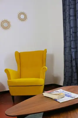 a yellow chair in a room with a coffee table at Appartement Centre Historique in LʼIsle-sur-la-Sorgue
