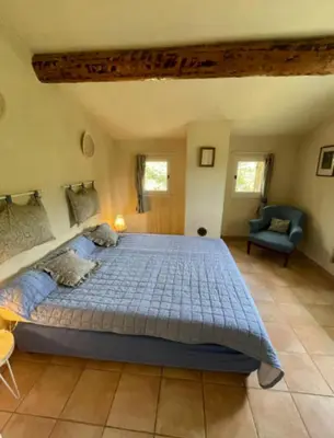 a bedroom with a large bed and a chair at Domaine au cœur du Colorado Provençal in Gignac