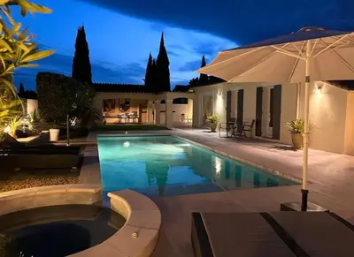 a swimming pool with an umbrella next to a house at Manava in Cheval-Blanc