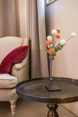 a vase with flowers on a table next to a chair at La Villa des Cedres in Bonnieux