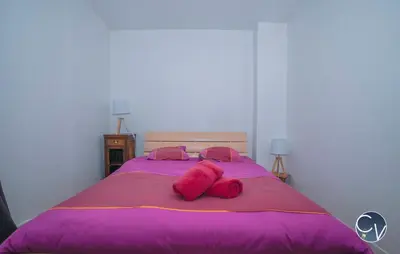 a purple bed with two pink pillows on it at Maison entière à 300m du centre in LʼIsle-sur-la-Sorgue