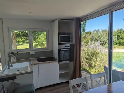 a kitchen with white cabinets and a large window at Cottage with Natural Pool in LʼIsle-sur-la-Sorgue