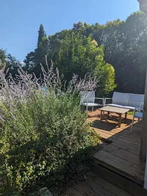 a wooden deck with a picnic table and benches at Cottage with Natural Pool in LʼIsle-sur-la-Sorgue