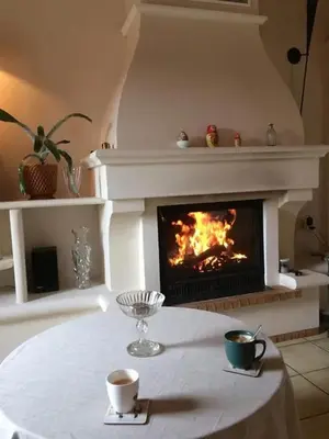 a table with two cups and a fireplace at La Maison Rose in LʼIsle-sur-la-Sorgue