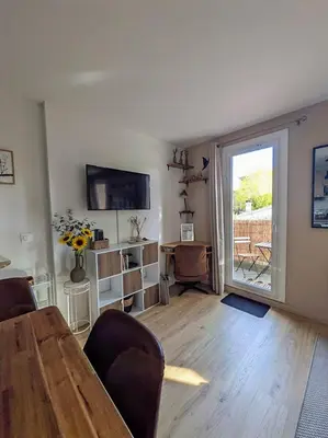 a living room with a wooden table and a television at Le Colibri - studio paisible et raffiné au sud d'Aix in Aix-en-Provence