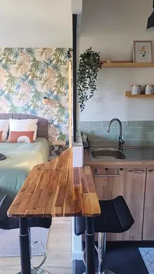 a kitchen with a wooden table next to a bed at Le Colibri - studio paisible et raffiné au sud d'Aix in Aix-en-Provence