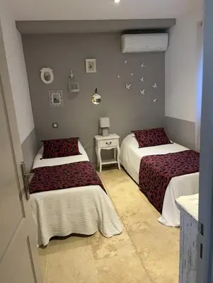 a bedroom with two beds and a table with a lamp at Mas provençal au coeur de L'Isle-sur-la-Sorgue in LʼIsle-sur-la-Sorgue