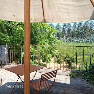 a table and a chair under an umbrella on a porch at gîtes carita in Cabannes