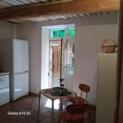a kitchen with a table and chairs and a refrigerator at gîtes carita in Cabannes