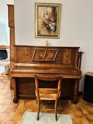 a wooden piano with a chair and a painting on the wall at Villa Marie-Rose in Saint-Didier