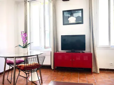 a living room with a tv and a table with chairs at Appart de charme CLIM 37m2 T1 Hôtel de ville in Aix-en-Provence