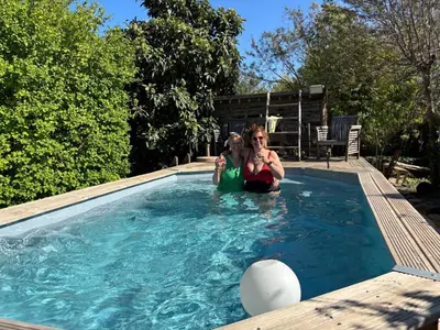 two women are sitting in a swimming pool at Chambres et table d'hôtes Au Brabo in Mormoiron