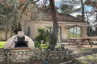 a stone oven in a yard with a picnic table at Gîte du Jonquas in Velleron