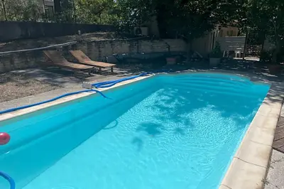 a fence next to a swimming pool in a yard at Gîte du Jonquas in Velleron