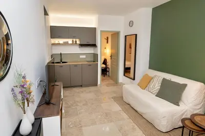 a living room with a white couch and a kitchen at Suite Vert Provence - Hypercentre - Wifi in Apt
