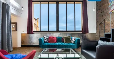 a living room with a blue couch and a large window at Aix-en-Provence, Centre ville quartier Mazarin, magnifique loft in Aix-en-Provence