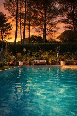 a large blue swimming pool with a sunset in the background at Bienvenue à la villa Bellavista in Pertuis