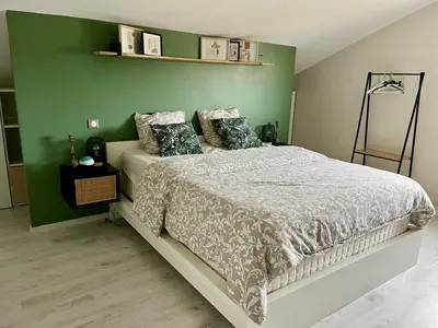 a bedroom with a bed with a green wall at Le Mas des platanes-piscine-gîte-Clim-parking in Monteux