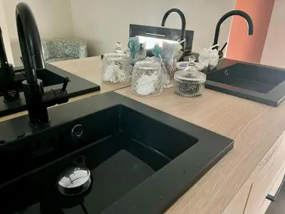 a kitchen counter with a black sink and two mirrors at Le Mas des platanes-piscine-gîte-Clim-parking in Monteux