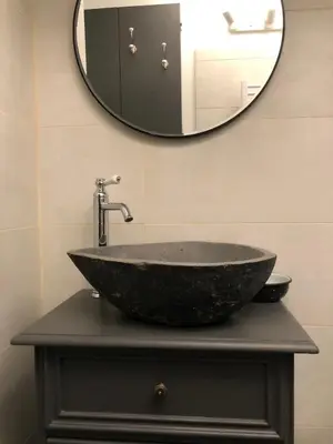 a bathroom sink with a large stone bowl and a mirror at studio au coeur de Lacoste in Lacoste