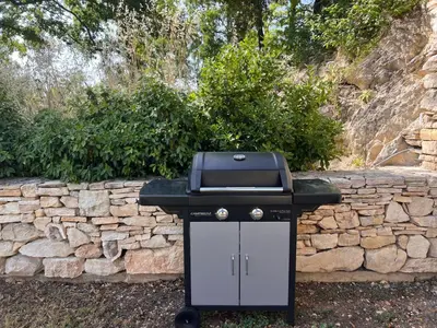 a bbq grill sitting in front of a stone wall at Le Grand Hermas in Saint-Martin-de-Castillon